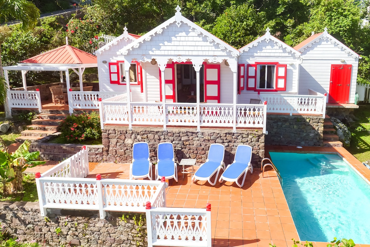 Flamboyant Cottage, a white Saban vacation rental with red shutters and a pool terrace in Windwardside